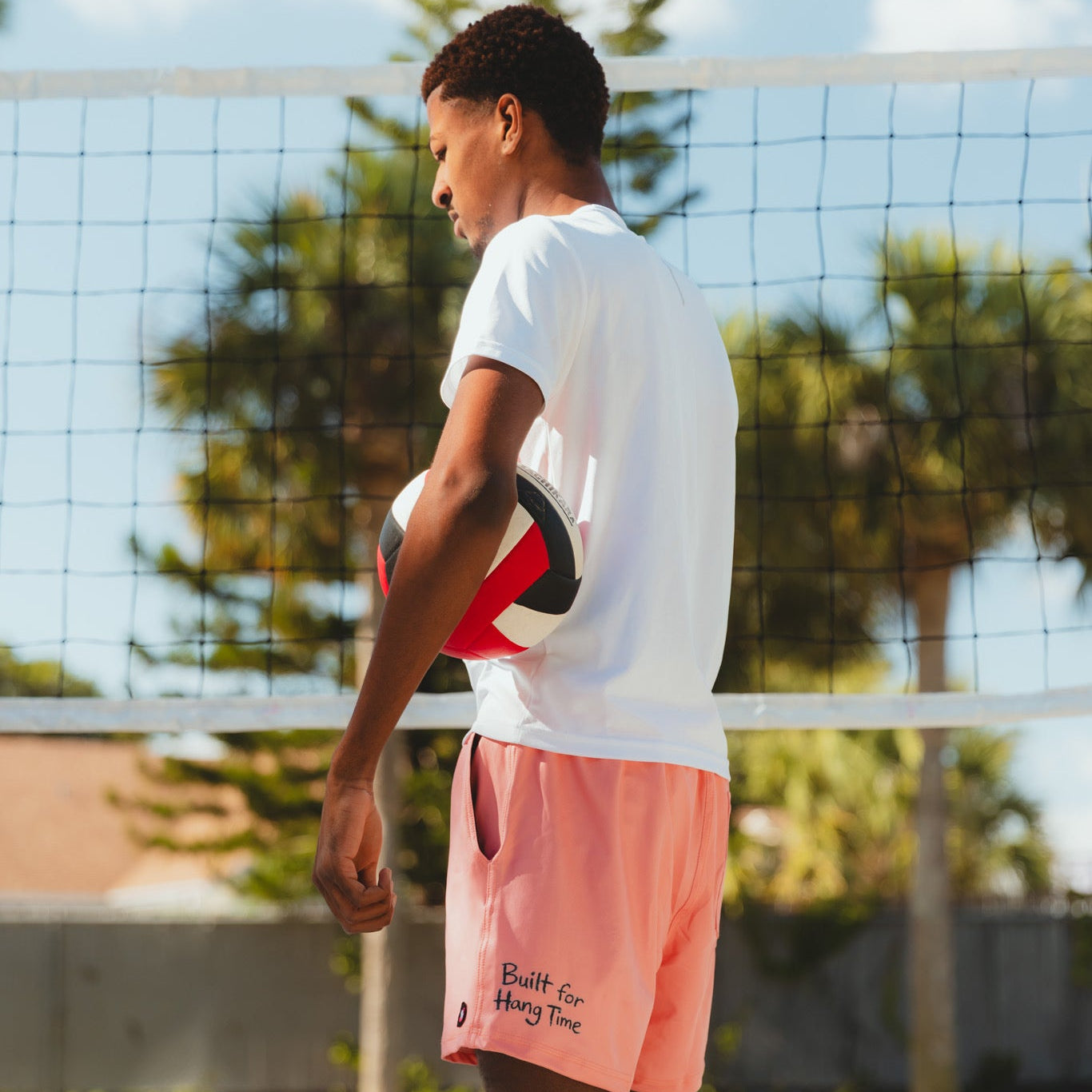 Person playing volleyball on a court with trees and sky in the background