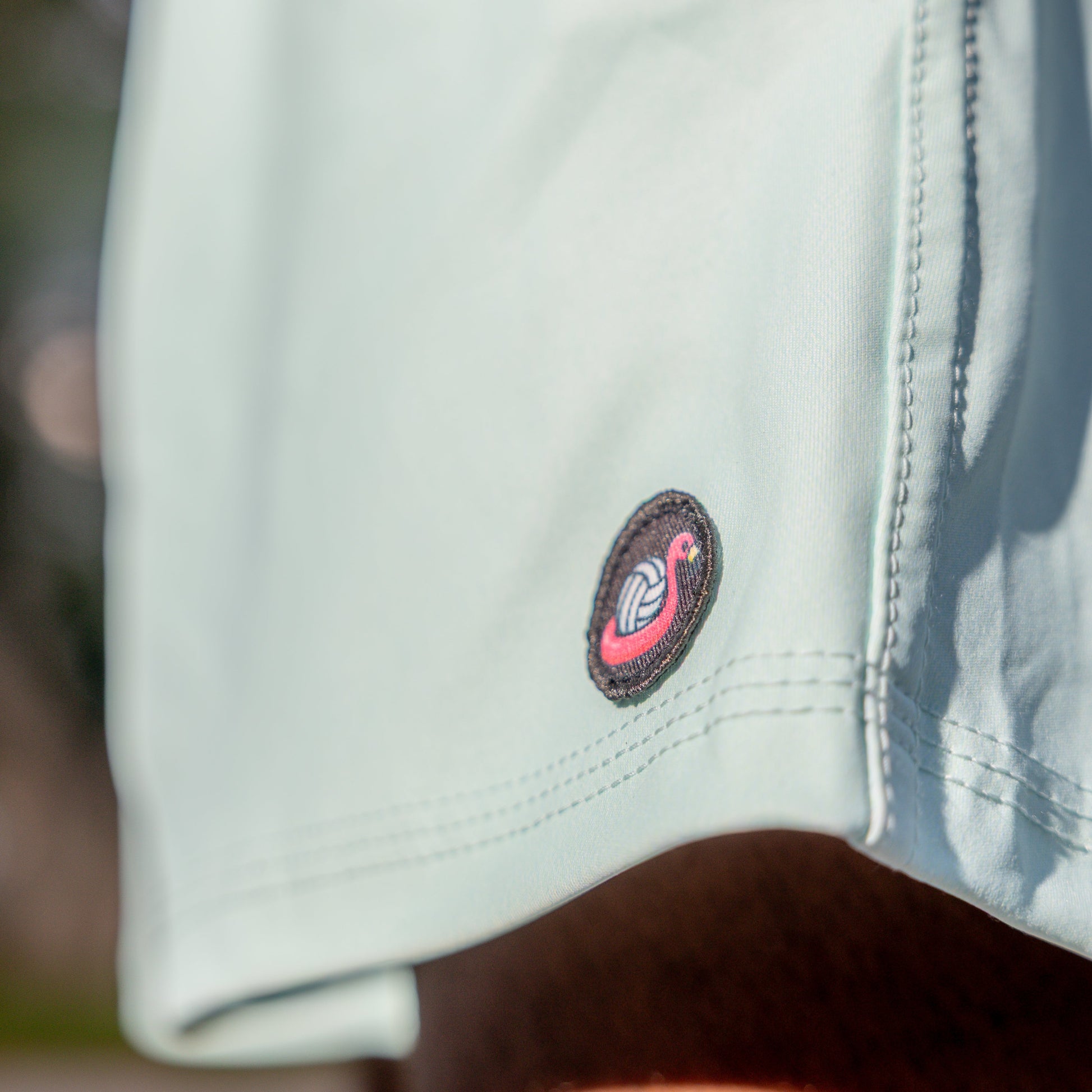 Light green shorts with a logo on the pocket, blurred background