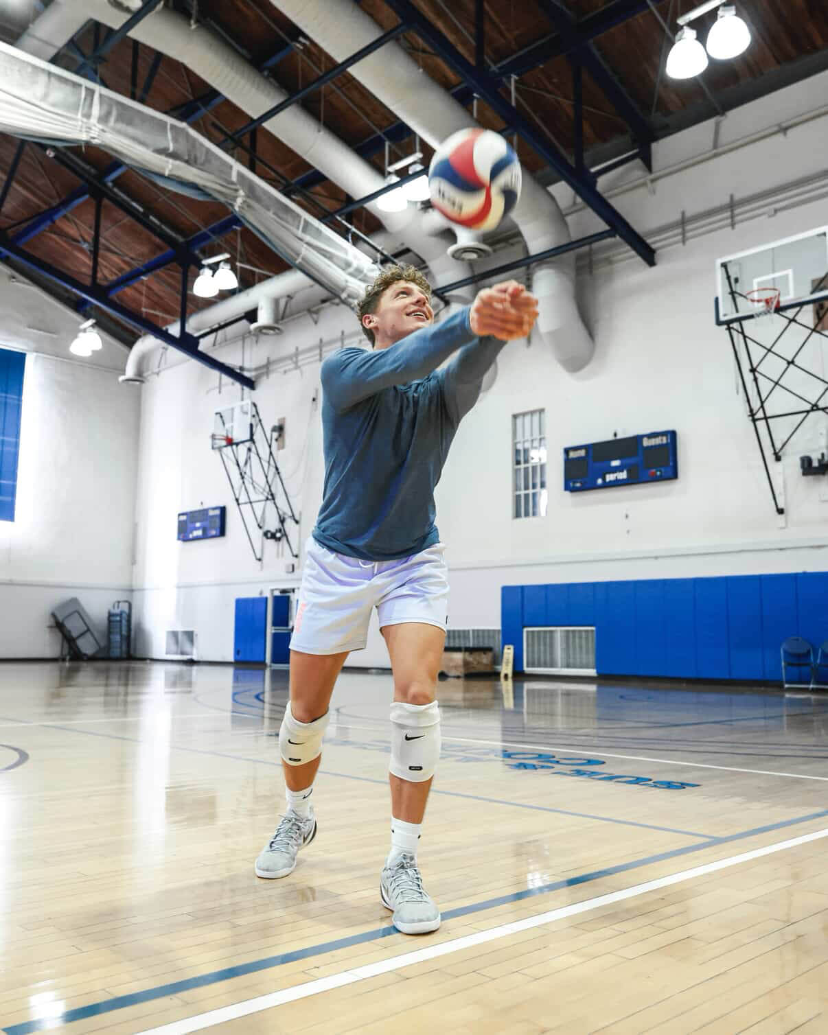 Person passing a volleyball in an indoor gym.