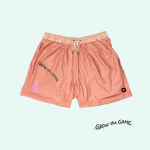 Pink shorts with 'Grow the Game' text on a light pink background