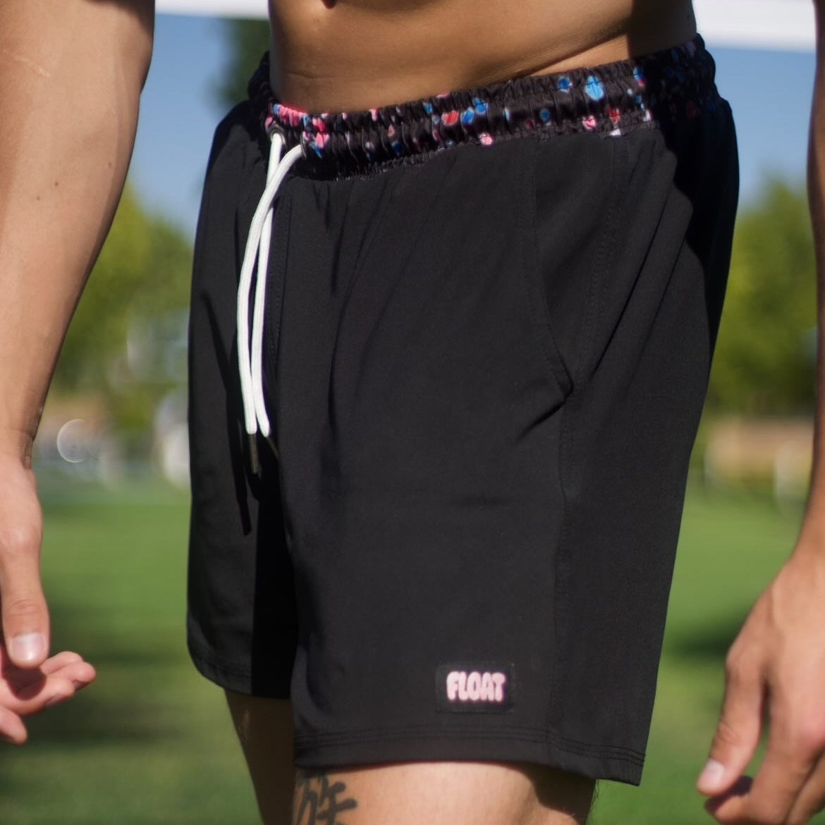 Person wearing black shorts with a colorful waistband on a grassy field.